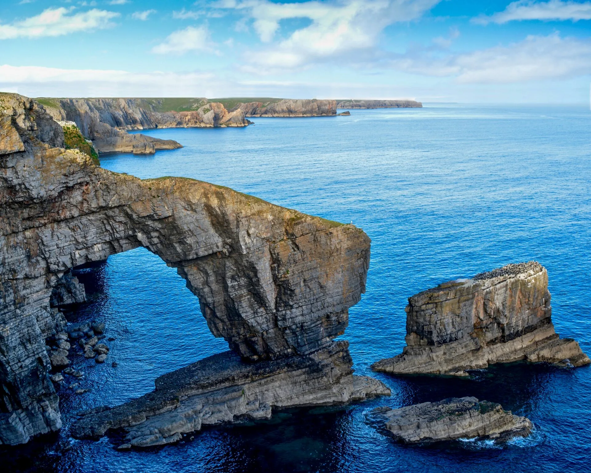 brown and green rock formation on blue sea under blue sky during daytime