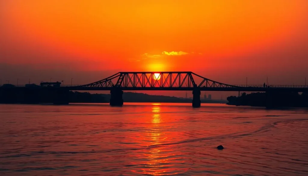 Generate an image of the Howrah Bridge at sunset with the Hooghly River flowing beneath it.
