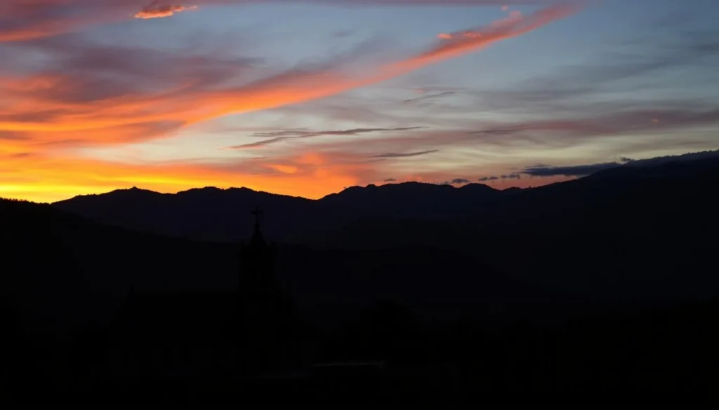 Sunset view over Tlalmanalco with the town's church silhouetted against the colorful sky and mountains