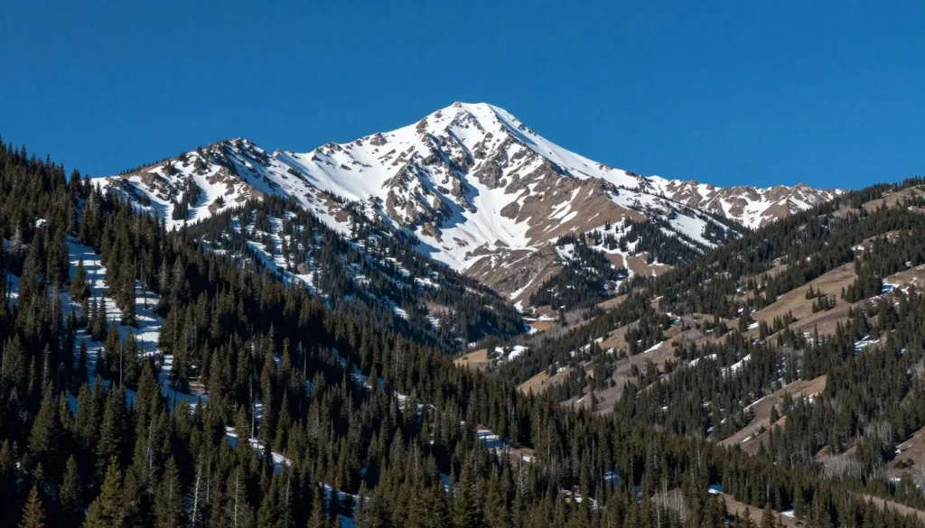 Mountain vista showing Pikes Peak rising above forested slopes under blue sky Mountain vista showing Pikes Peak rising above forested slopes under blue sky
