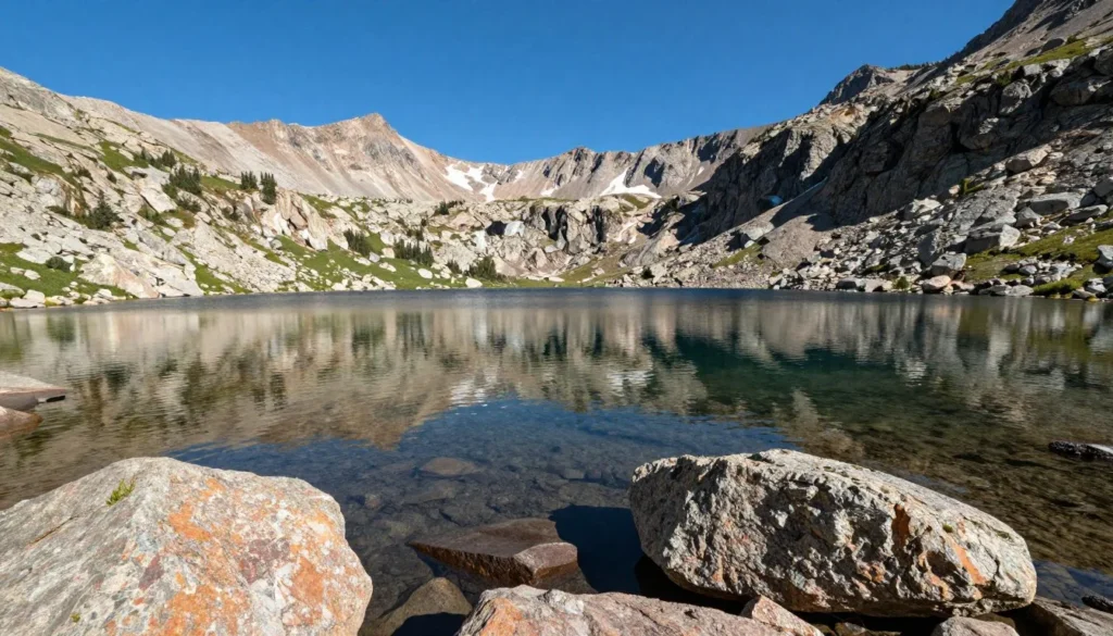 Pristine alpine lake in Colorado mountains with rocky shores and peaks