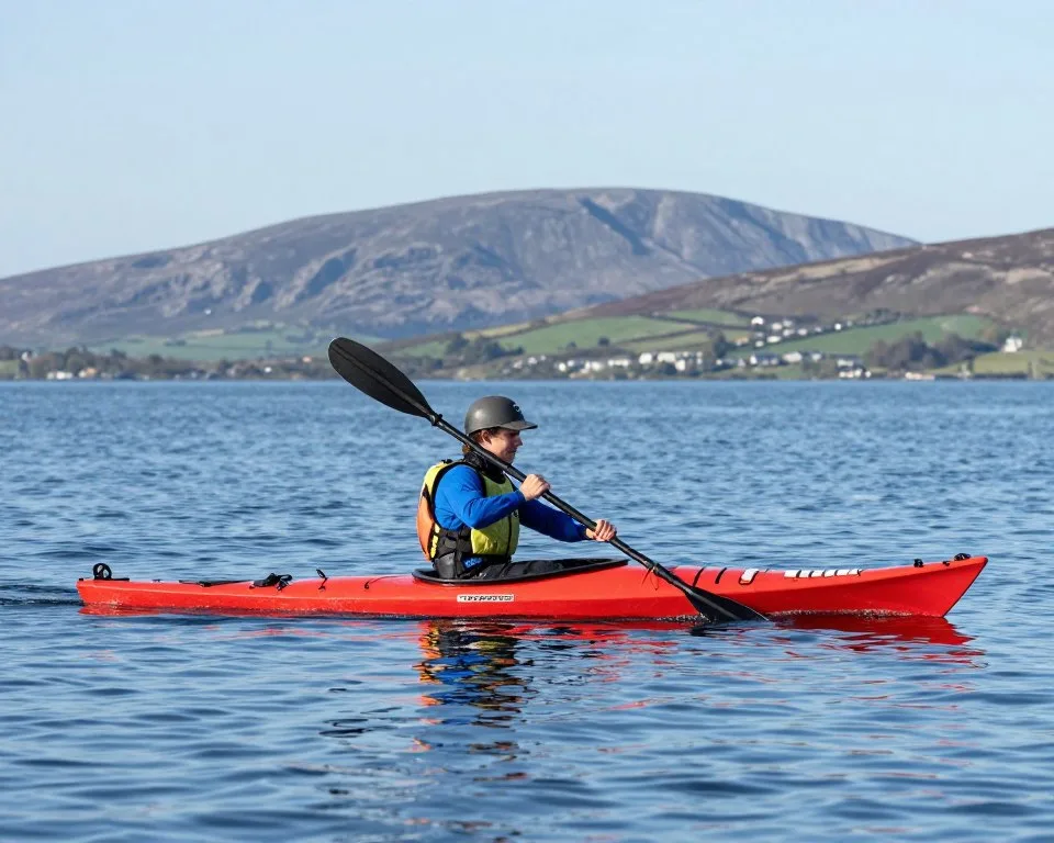 Person kayaking on calm waters of Tralee Bay with mountain backdrop Person kayaking on calm waters of Tralee Bay with mountain backdrop